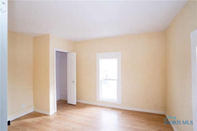 spare room featuring baseboards and light wood finished floors