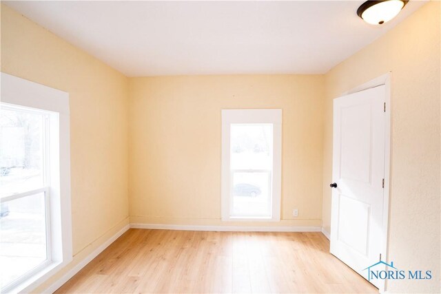 unfurnished room with baseboards, a healthy amount of sunlight, and light wood finished floors