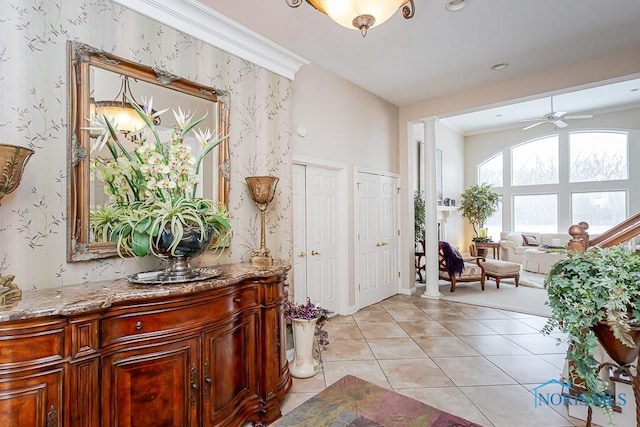 tiled foyer with ceiling fan, ornamental molding, and ornate columns