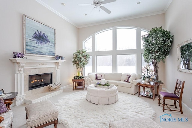 carpeted living room with ceiling fan, crown molding, and a fireplace