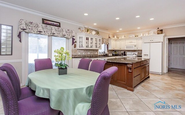 tiled dining room featuring sink and ornamental molding