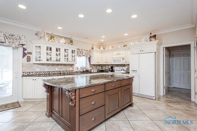 kitchen featuring a center island, dark stone counters, white cabinetry, and white appliances