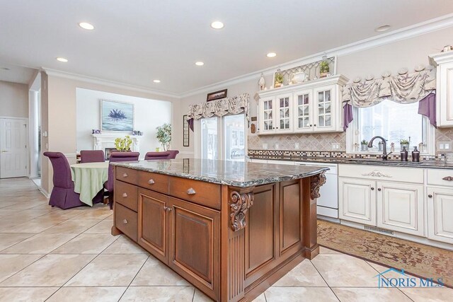 kitchen with dishwasher, white cabinetry, decorative backsplash, dark stone counters, and plenty of natural light