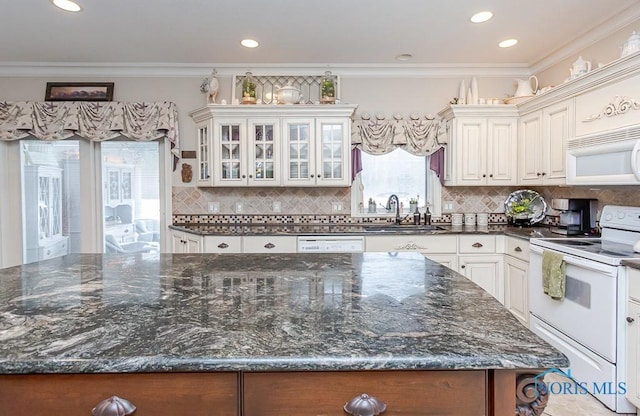 kitchen featuring crown molding, sink, white cabinetry, dark stone counters, and white appliances