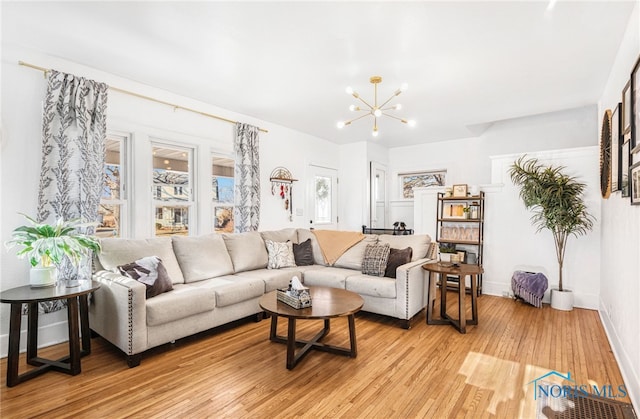 living area featuring a notable chandelier, light wood-style flooring, and baseboards