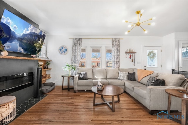 living area with an inviting chandelier, a fireplace with flush hearth, and wood finished floors