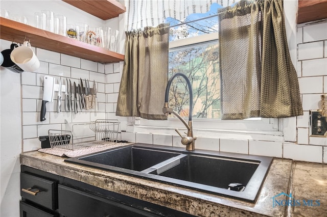 kitchen with open shelves, dark cabinets, decorative backsplash, and a sink