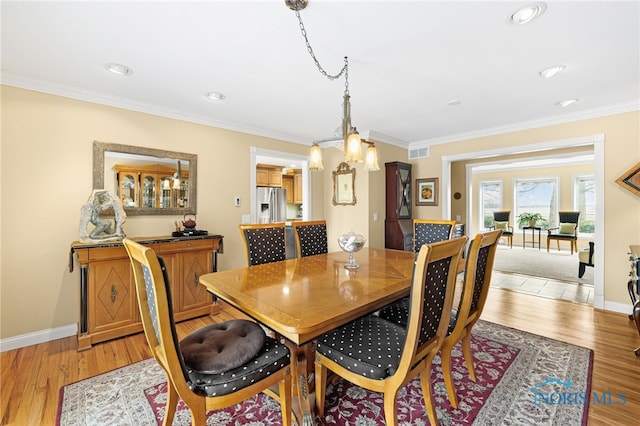 dining area featuring light wood-type flooring and crown molding