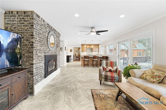 living room with ceiling fan, crown molding, and a fireplace