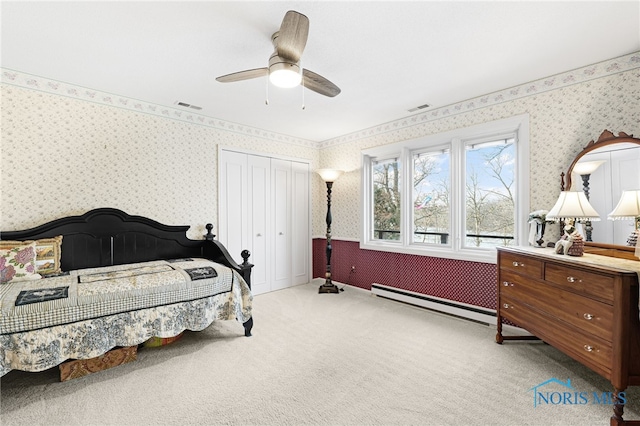 carpeted bedroom with ceiling fan and a baseboard heating unit