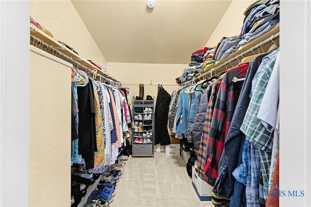 spacious closet with light colored carpet and lofted ceiling