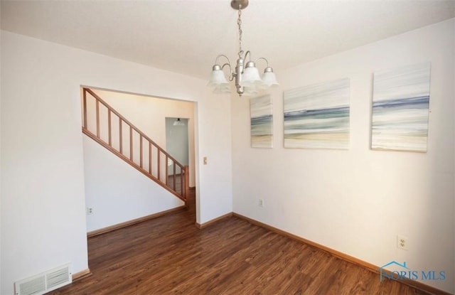 empty room with dark hardwood / wood-style floors and a notable chandelier