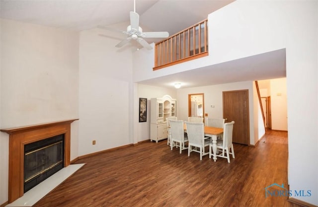 dining space with dark wood-type flooring, ceiling fan, and high vaulted ceiling