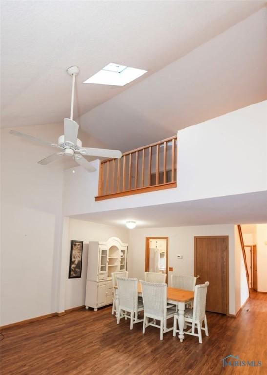 dining room with hardwood / wood-style flooring, ceiling fan, a skylight, and high vaulted ceiling