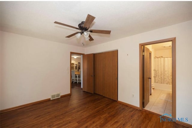 unfurnished bedroom featuring dark hardwood / wood-style floors, a closet, ceiling fan, and ensuite bathroom