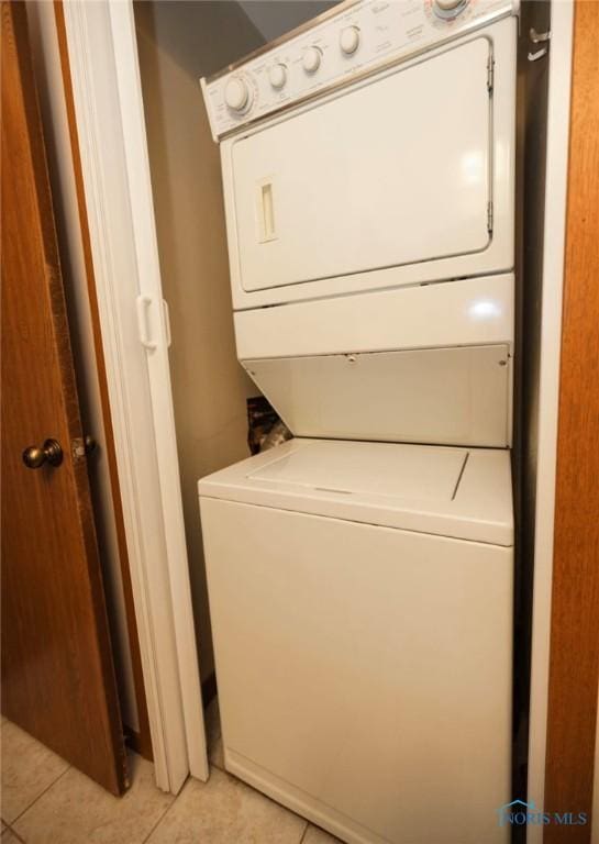 laundry room with stacked washer / drying machine and light tile patterned floors