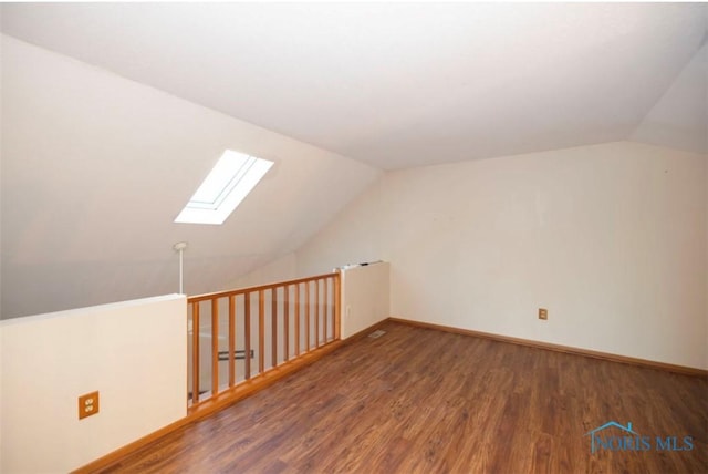 additional living space featuring dark hardwood / wood-style floors and lofted ceiling with skylight