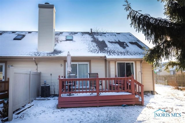 snow covered house with a wooden deck and central air condition unit