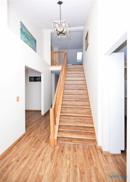 stairs featuring hardwood / wood-style floors and a notable chandelier