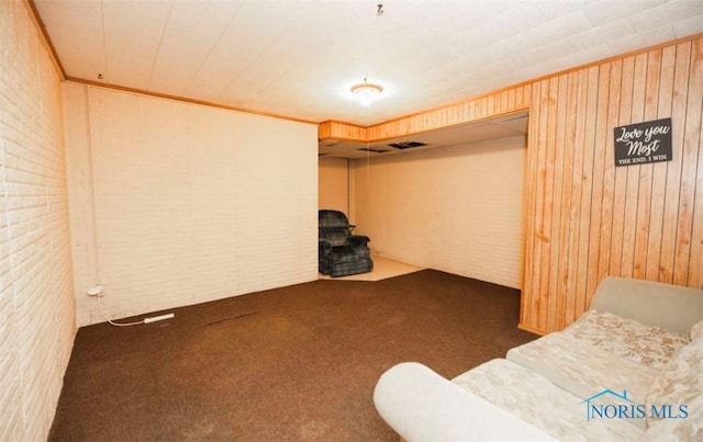 basement featuring dark colored carpet and wooden walls