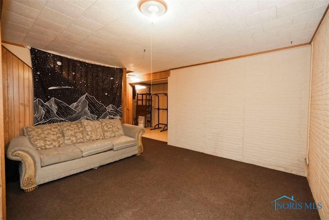 unfurnished living room featuring ornamental molding, dark carpet, and wood walls