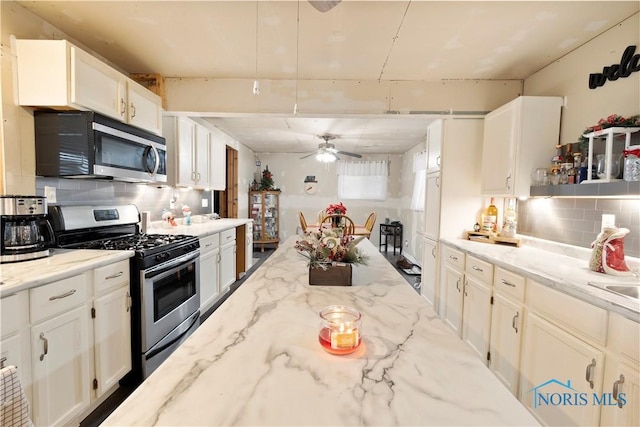 kitchen with ceiling fan, backsplash, white cabinetry, light stone countertops, and appliances with stainless steel finishes