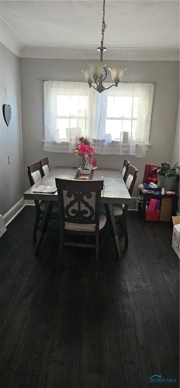 dining area with ornamental molding, dark wood-type flooring, and an inviting chandelier