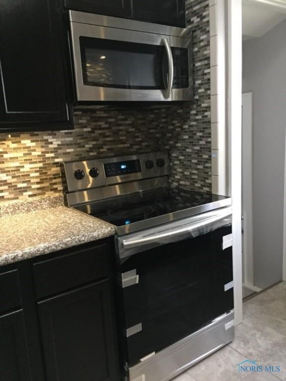 kitchen featuring stainless steel appliances, tasteful backsplash, light stone countertops, and light tile patterned floors