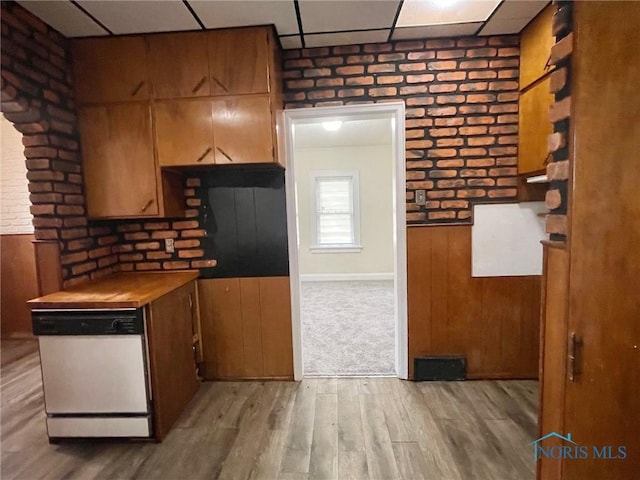 kitchen featuring brick wall, dishwasher, a paneled ceiling, wood walls, and light hardwood / wood-style flooring