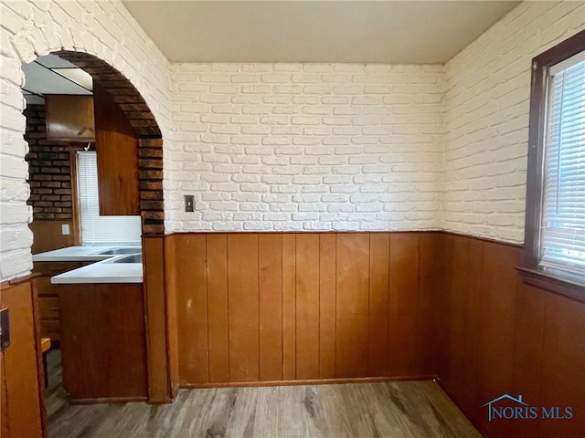 interior space with a healthy amount of sunlight, wooden walls, light hardwood / wood-style flooring, and brick wall