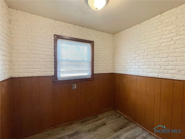 empty room with brick wall and dark hardwood / wood-style flooring