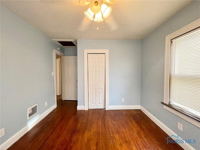 unfurnished bedroom featuring ceiling fan, dark hardwood / wood-style floors, and multiple windows