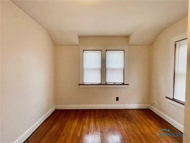 spare room with hardwood / wood-style floors and lofted ceiling