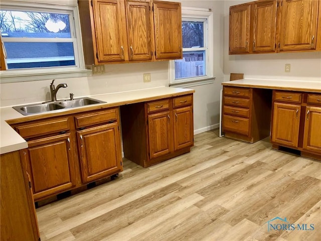 kitchen featuring sink, light hardwood / wood-style flooring, and built in desk