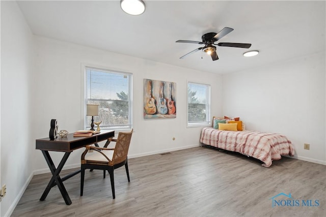 bedroom with ceiling fan, multiple windows, and hardwood / wood-style floors