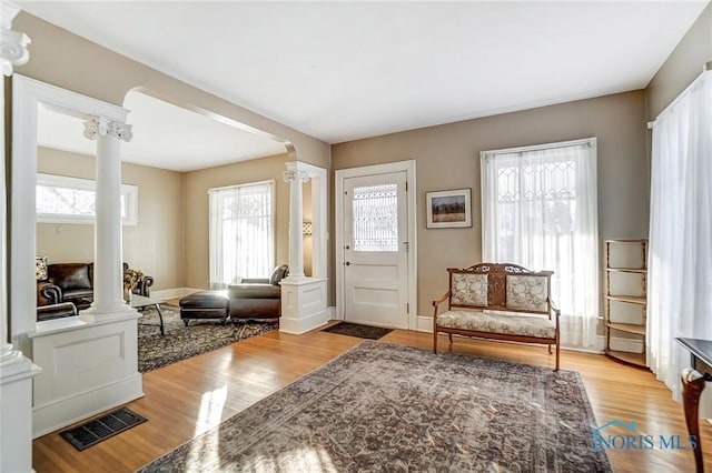 sitting room featuring decorative columns, plenty of natural light, and light hardwood / wood-style floors