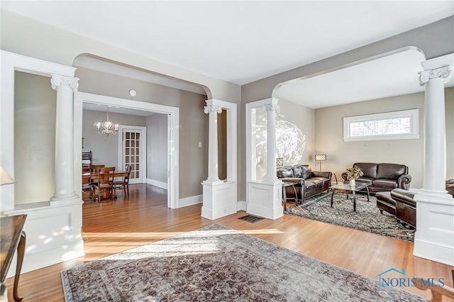 living room featuring decorative columns, hardwood / wood-style flooring, and a notable chandelier