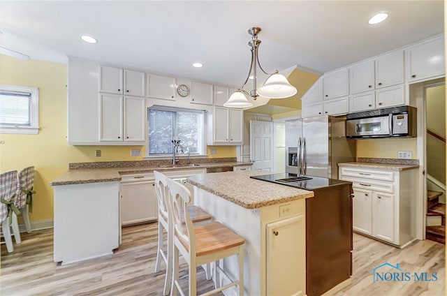 kitchen featuring a kitchen island, white cabinets, decorative light fixtures, and stainless steel appliances