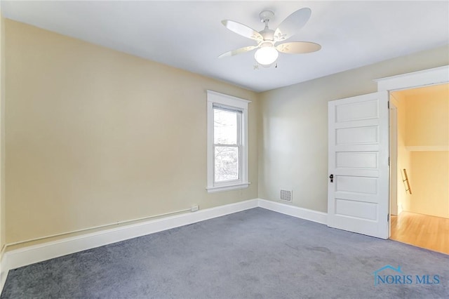 unfurnished room featuring ceiling fan and dark colored carpet