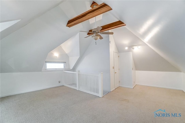 additional living space with light colored carpet, vaulted ceiling with beams, and ceiling fan