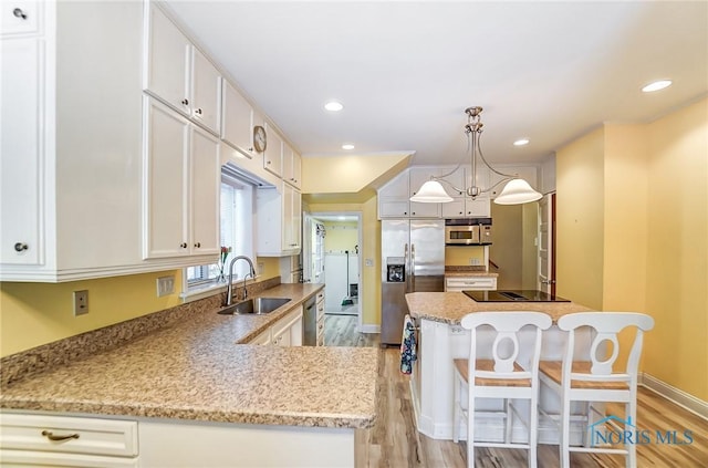 kitchen featuring pendant lighting, white cabinetry, stainless steel appliances, light hardwood / wood-style floors, and sink