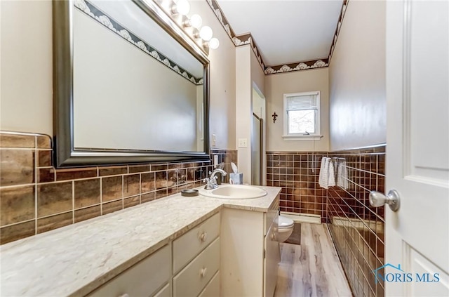 bathroom with vanity, hardwood / wood-style flooring, tile walls, and toilet