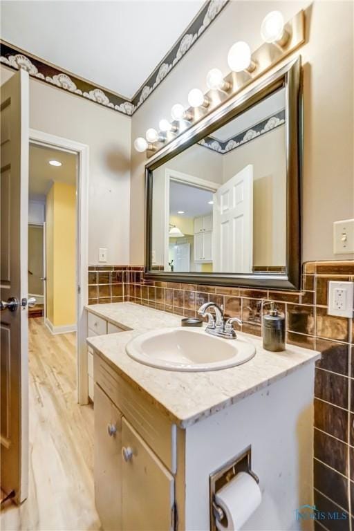 bathroom featuring hardwood / wood-style floors, vanity, and tasteful backsplash