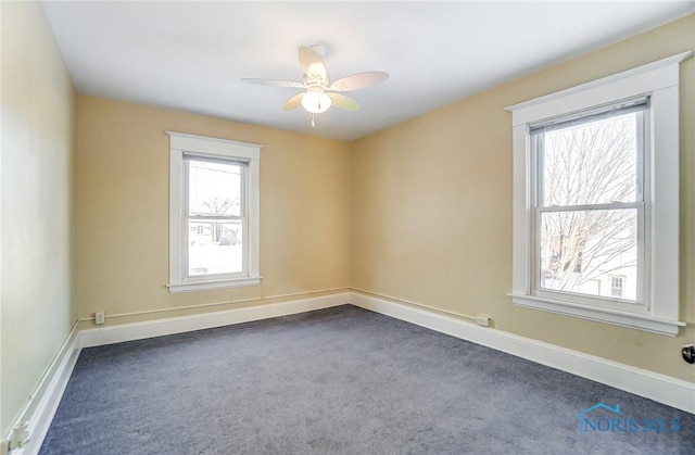 spare room featuring ceiling fan and dark carpet