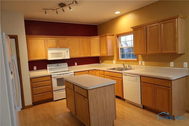 kitchen featuring white appliances, sink, a kitchen island, and light hardwood / wood-style flooring