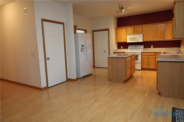 kitchen featuring sink, white appliances, a center island, light wood-type flooring, and light brown cabinets