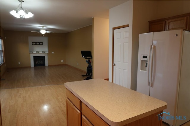 kitchen featuring a center island, hanging light fixtures, light wood-type flooring, white refrigerator with ice dispenser, and ceiling fan with notable chandelier