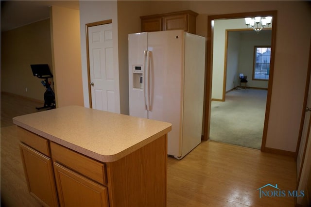 kitchen featuring white refrigerator with ice dispenser, a center island, a notable chandelier, and light hardwood / wood-style flooring