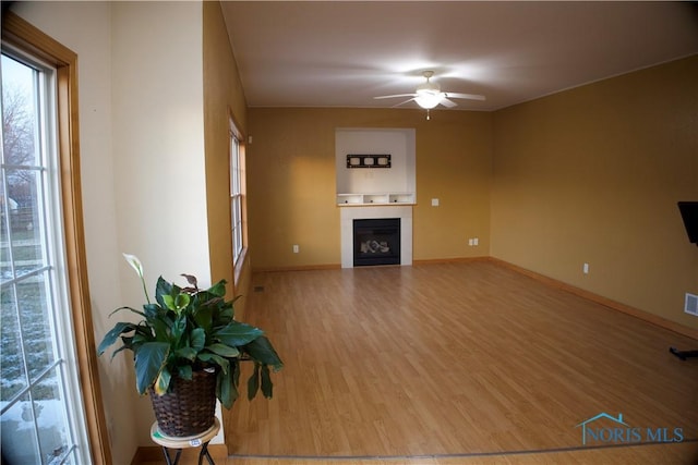 unfurnished living room with ceiling fan and wood-type flooring