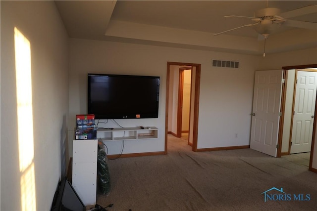 living room with ceiling fan, light colored carpet, and a raised ceiling